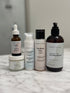 Acne and hyperpigmentation skincare set with green tea cleanser, niacinamide serum, snail mucin cream, and moisturizing butter on marble surface