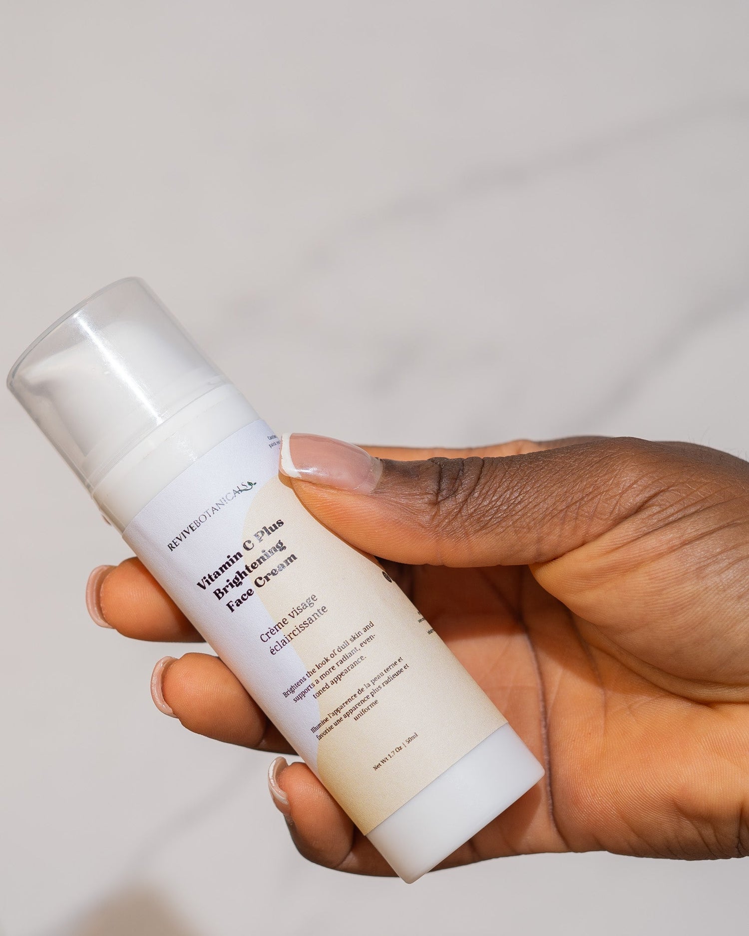 Vitamin C Plus Brightening Face Cream bottle held in hand.