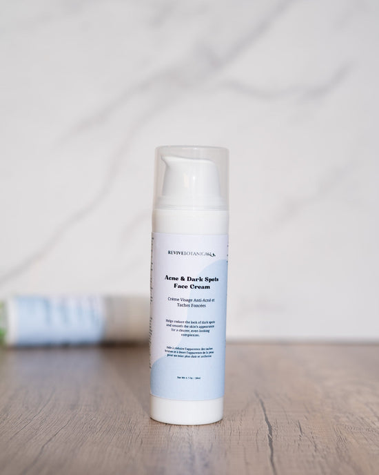 Acne & Dark Spots Face Cream bottle on a wooden surface.